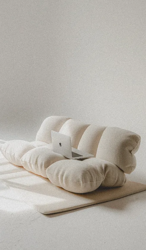 Laptop resting on a sculptural cream fabric lounge