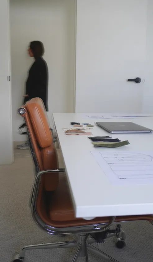 Studio workspace with leather chair and drawings on a white desk