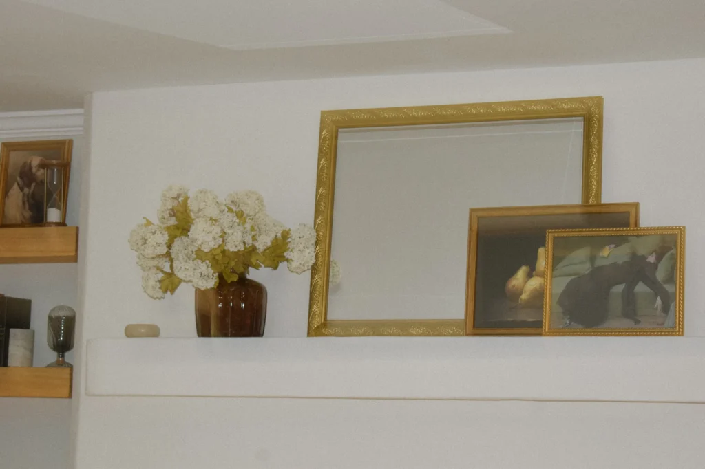 The Curated Coastal Home, North Carolina: Styled living room fireplace with gilded mirror and fresh florals