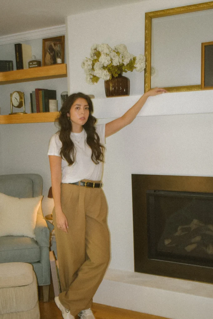 The Curated Coastal Home, North Carolina: Alexis Woodbury Earman beside the styled fireplace mantel